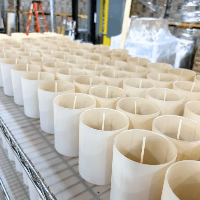 Rows of decorated white glass jars on a production line